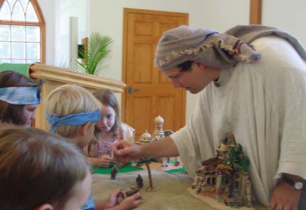 Father Frank helps the kids with a nativity scene