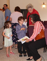 three families are represented in this photo of adults talking to children after the service